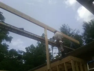 Carpenter setting a ridge beam over a new addition frame — Ice Dam Removal by Roofing Brothers in Latham