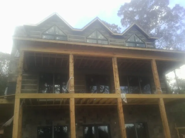 Dormers and porch framing on a large log home under construction — Roof Coating work by our crew in Latham