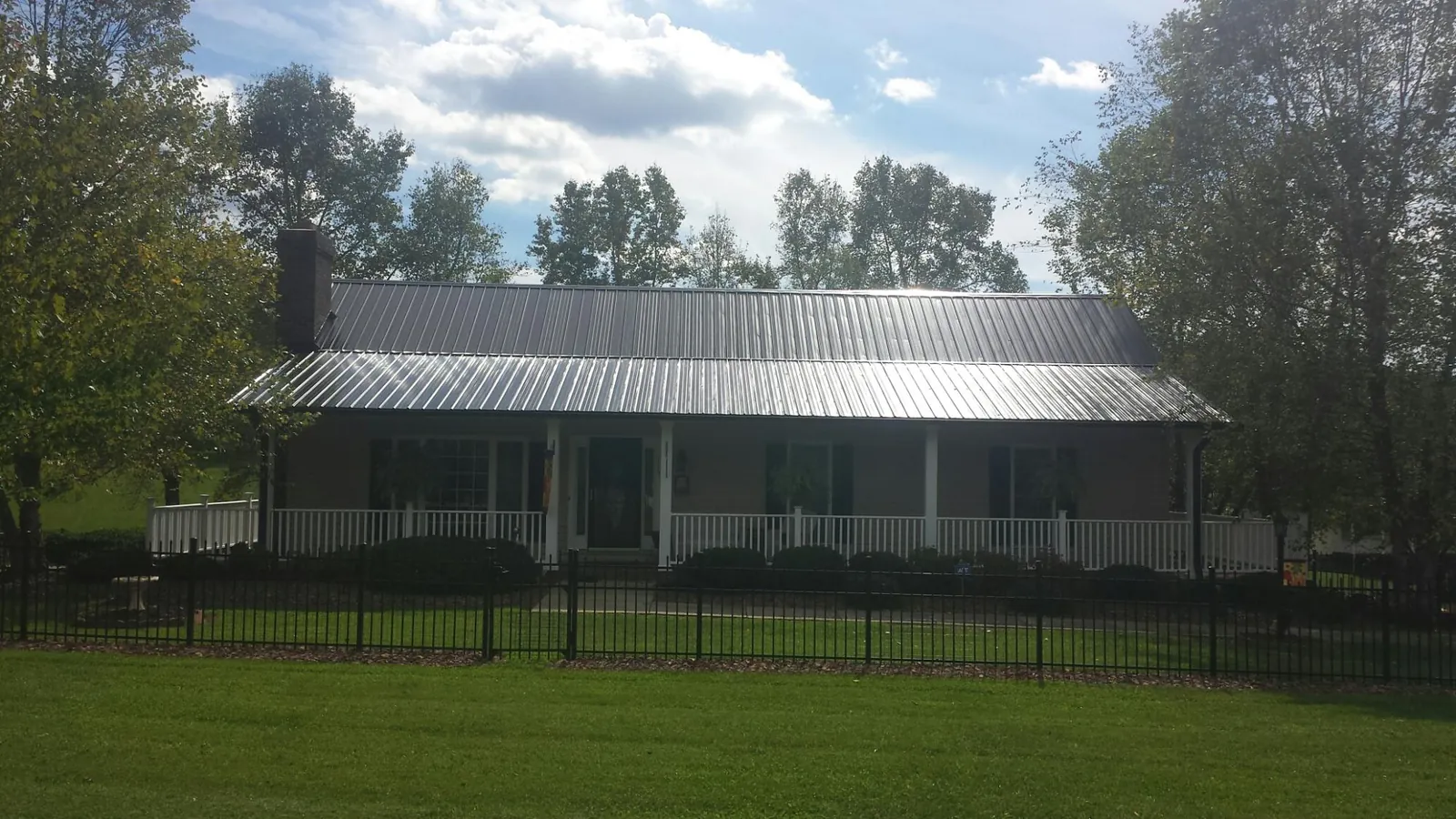 Gray metal roof on a brick ranch with a full width front porch — Gutter Guard Installation work by our crew in Latham