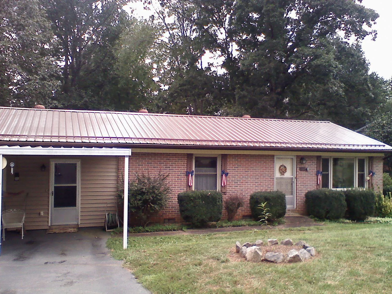 Bronze metal roof and carport on a brick ranch home — Roof Repair work by our crew in Latham