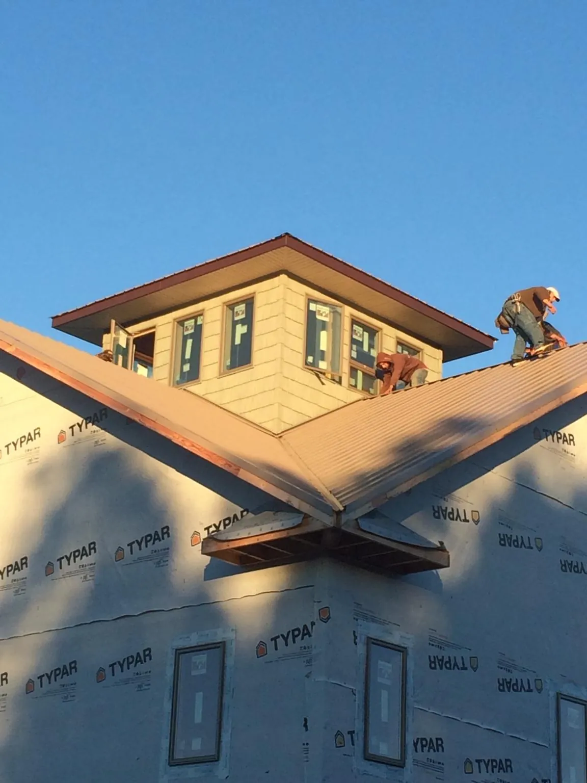 Roofers working around a rooftop cupola on a new metal roof at sunset — Roof Waterproofing in Latham by Roofing Brothers